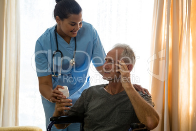 Female doctor examining senior man sitting on wheelchair