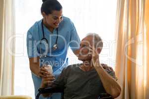 Female doctor examining senior man sitting on wheelchair