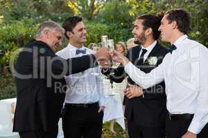 Groom and guests toasting glasses of champagne