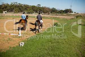 Two male friends riding horse in the ranch