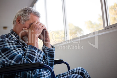 Side view of sad senior man sitting on wheelchair