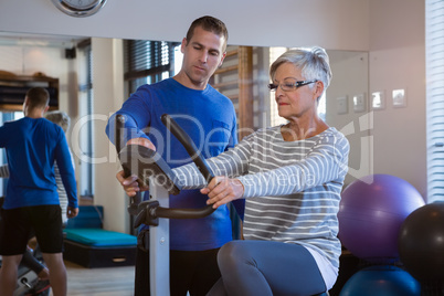 Physiotherapist showing workout record on exercise bike