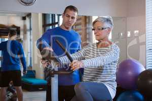 Physiotherapist showing workout record on exercise bike