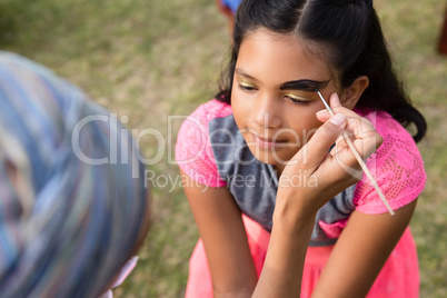 Cropped image of woman doing face paint on girl