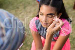 Cropped image of woman doing face paint on girl