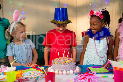 Friends looking at boy standing by cake