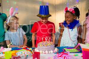 Friends looking at boy standing by cake