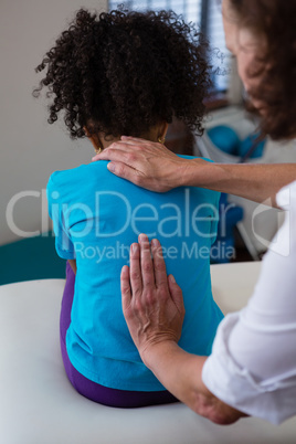 Physiotherapist giving back massage to girl patient