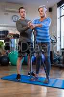 Male physiotherapist helping patient in performing exercise with resistance band