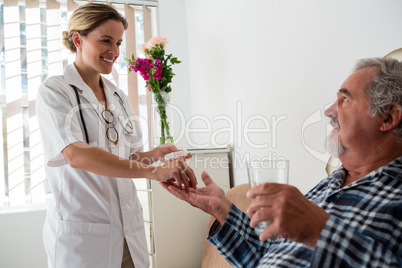 Female doctor giving medicines to senior patient