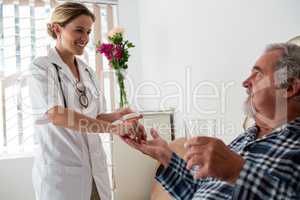 Female doctor giving medicines to senior patient