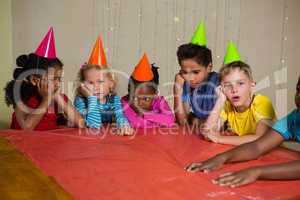 Bored children in part hat sitting at table