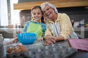 Granddaughter and grandmother posing while standing in the kitchen