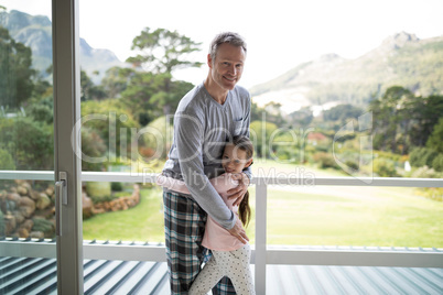 Smiling father and daughter embracing each other in balcony