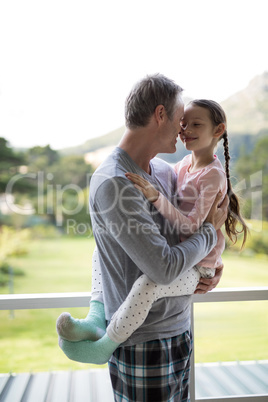 Smiling father and daughter embracing each other in balcony