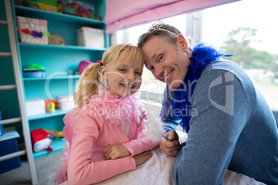Girl and father dressed as fairy sitting head to head