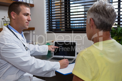 Physiotherapist writing prescription on clipboard for senior patient
