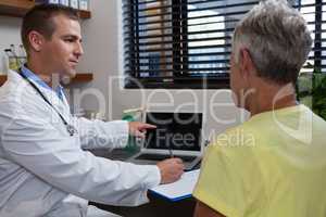 Physiotherapist writing prescription on clipboard for senior patient