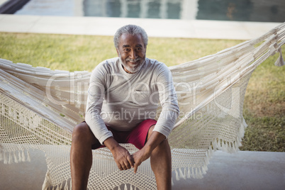 Smiling senior man sitting on hammock