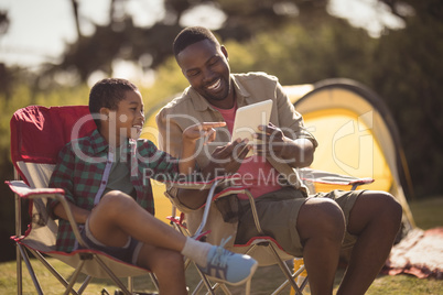 Father and son using digital tablet in park