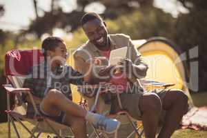 Father and son using digital tablet in park