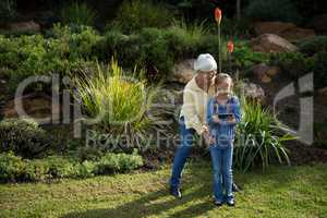 Grandmother and granddaughter using mobile phone in garden