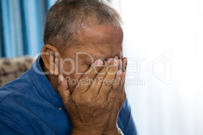 Close up of upset senior man covering eyes with hands