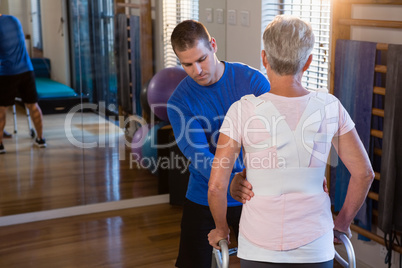 Physiotherapist assisting patient to walk with walking frame