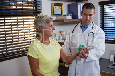 Physiotherapist assisting senior woman with stress ball exercise