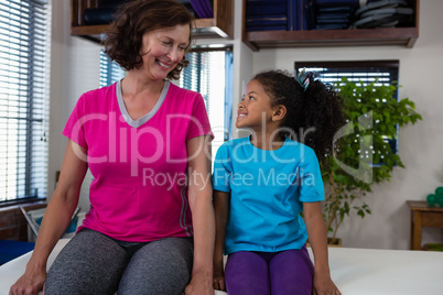 Girl and physiotherapist interacting on bed