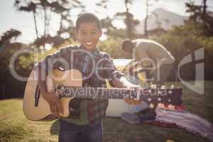 Smiling boy playing guitar in park