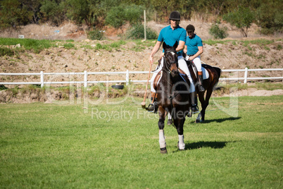 Two male jockeys riding horse in the ranch