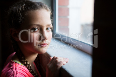Portrait of teenage girl standing near window