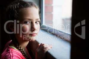 Portrait of teenage girl standing near window