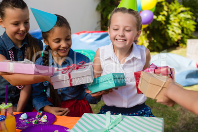 Smiling girl receiving gifts from friends