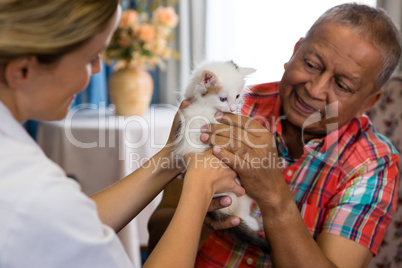 Female doctor and man playing with kitten at nursing home