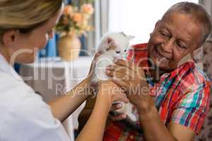 Female doctor and man playing with kitten at nursing home