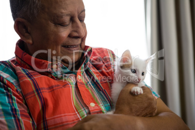 Senior man playing with kitten at nursing home