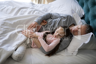 Father and daughter sleeping together on bed in bedroom