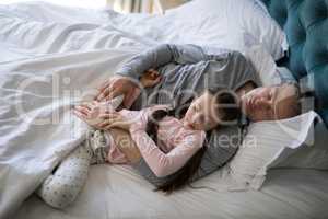 Father and daughter sleeping together on bed in bedroom