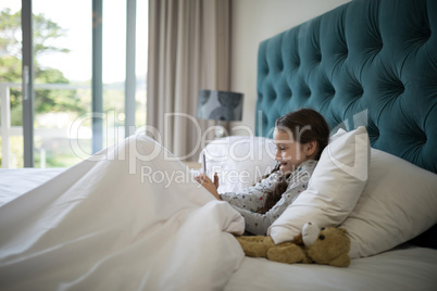 Girl using mobile phone on bed in bedroom