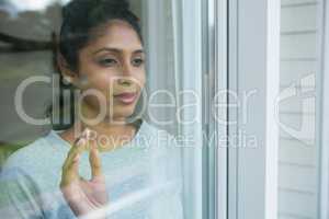Thoughtful woman seen through glass