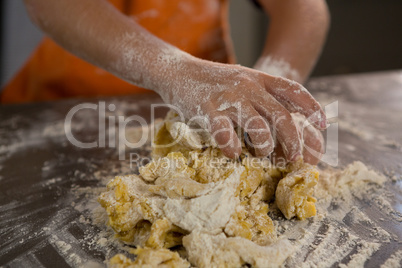 Mid section of boy kneading dough