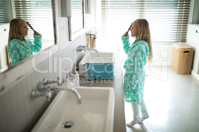 Girl combing her hair in bathroom