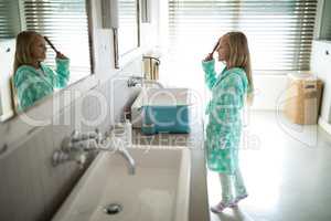 Girl combing her hair in bathroom