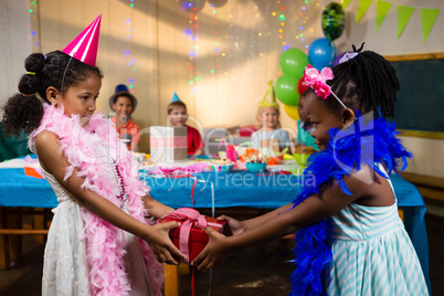 Side view of girl giving gift to friend