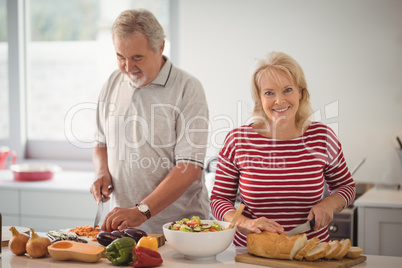 Smiling senior couple preparing food in kitchen