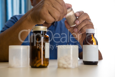 Midsection of senior man taking medicines in nursing home