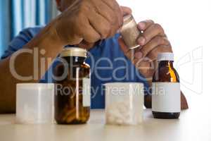 Midsection of senior man taking medicines in nursing home