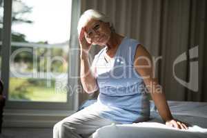 Tense senior woman sitting on bed in bedroom